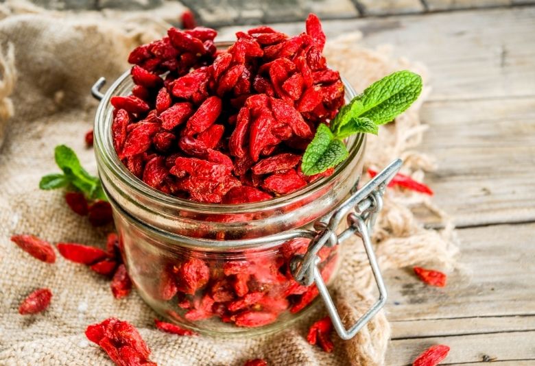 Un pot rempli de baies de Goji, reconnues pour leurs bienfaits nutritionnels, pouvant soutenir l'équilibre hormonal et la perte de poids à la ménopause.
