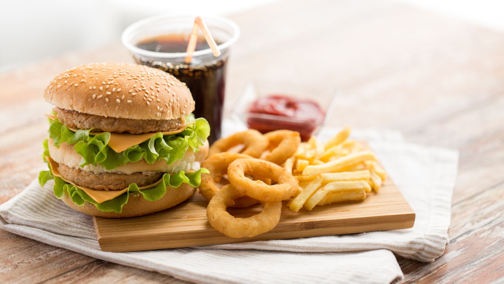 Burger, soda et frites, représentant les aliments ultra-transformés souvent consommés dans le cadre d'une alimentation déséquilibrée.