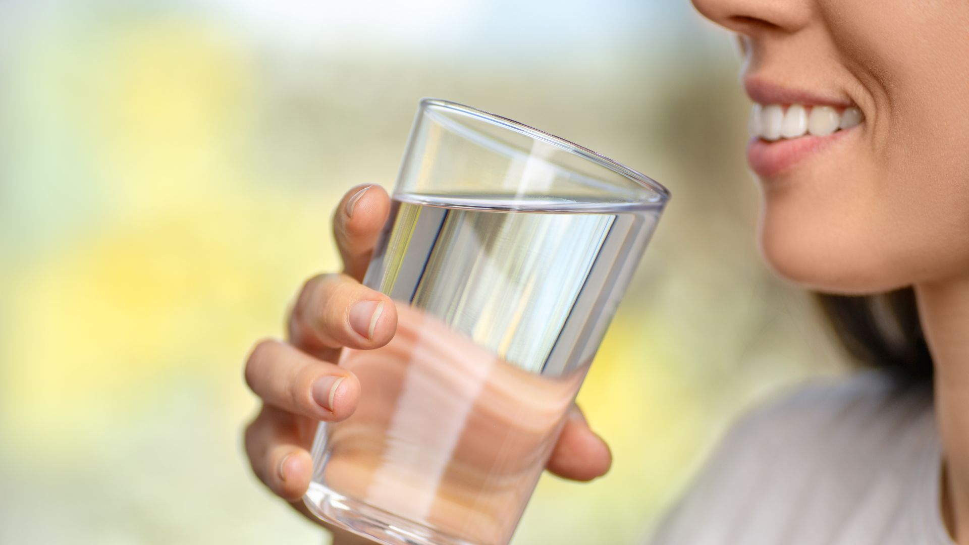 Femme buvant un verre d'eau, illustrant les bienfaits d'une bonne hydratation pour la perte de poids et le bien-être selon la médecine traditionnelle chinoise.