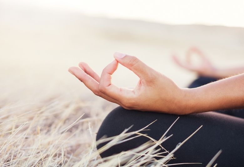 Femme méditant dans la nature, illustrant l'importance de la détente et de la gestion du stress pour améliorer la qualité du sommeil.