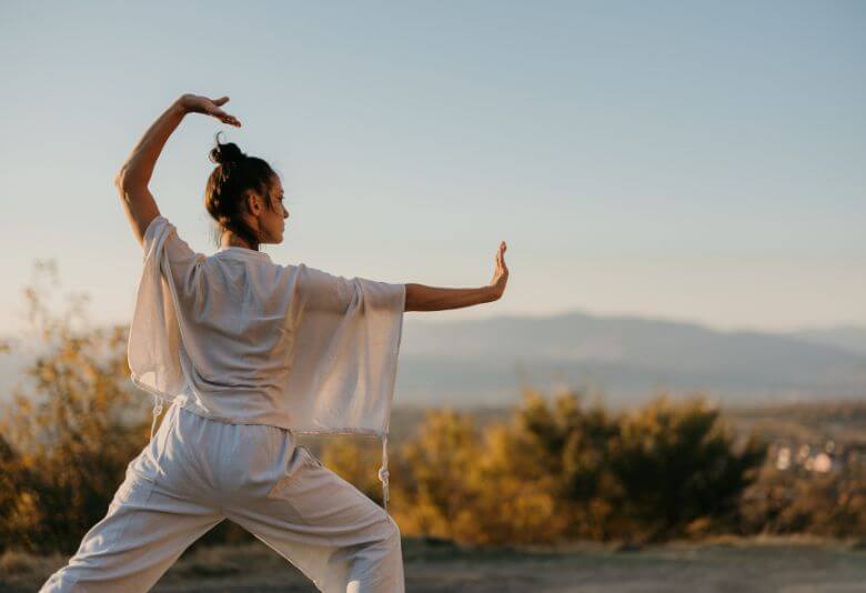 Femme pratiquant le Tai-chi-chuan en plein air, une activité bénéfique pour l'équilibre physique et mental, idéale pendant la ménopause.