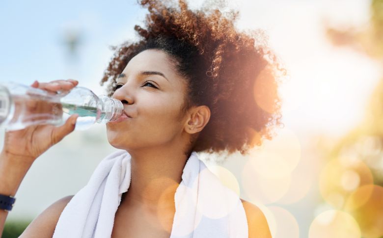 Femme buvant de l'eau, essentielle pour l'hydratation et la gestion du poids, à combiner avec une alimentation équilibrée pour de meilleurs résultats.