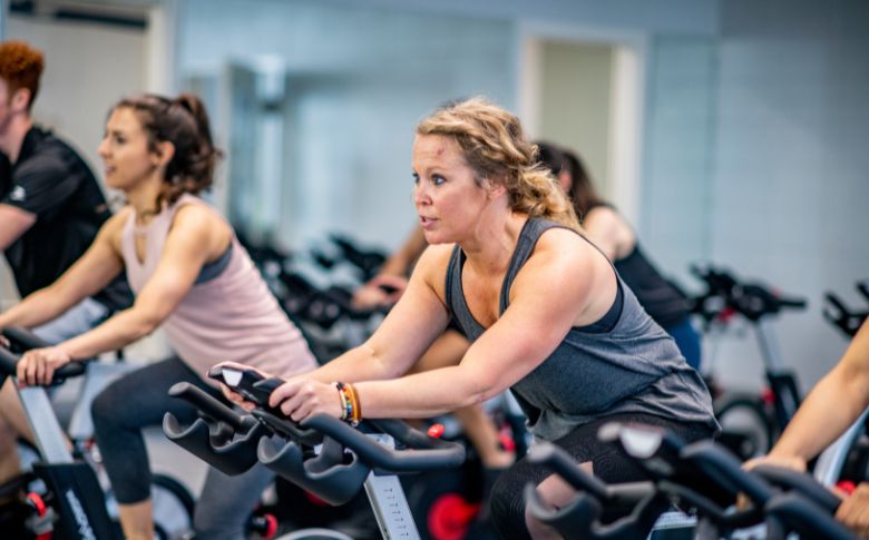 Femme faisant du vélo en salle, une activité cardio efficace pour soutenir la perte de poids à la ménopause tout en améliorant la forme physique.